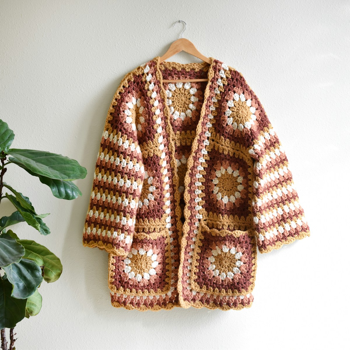 A crocheted granny-square jacket hanging on a wall