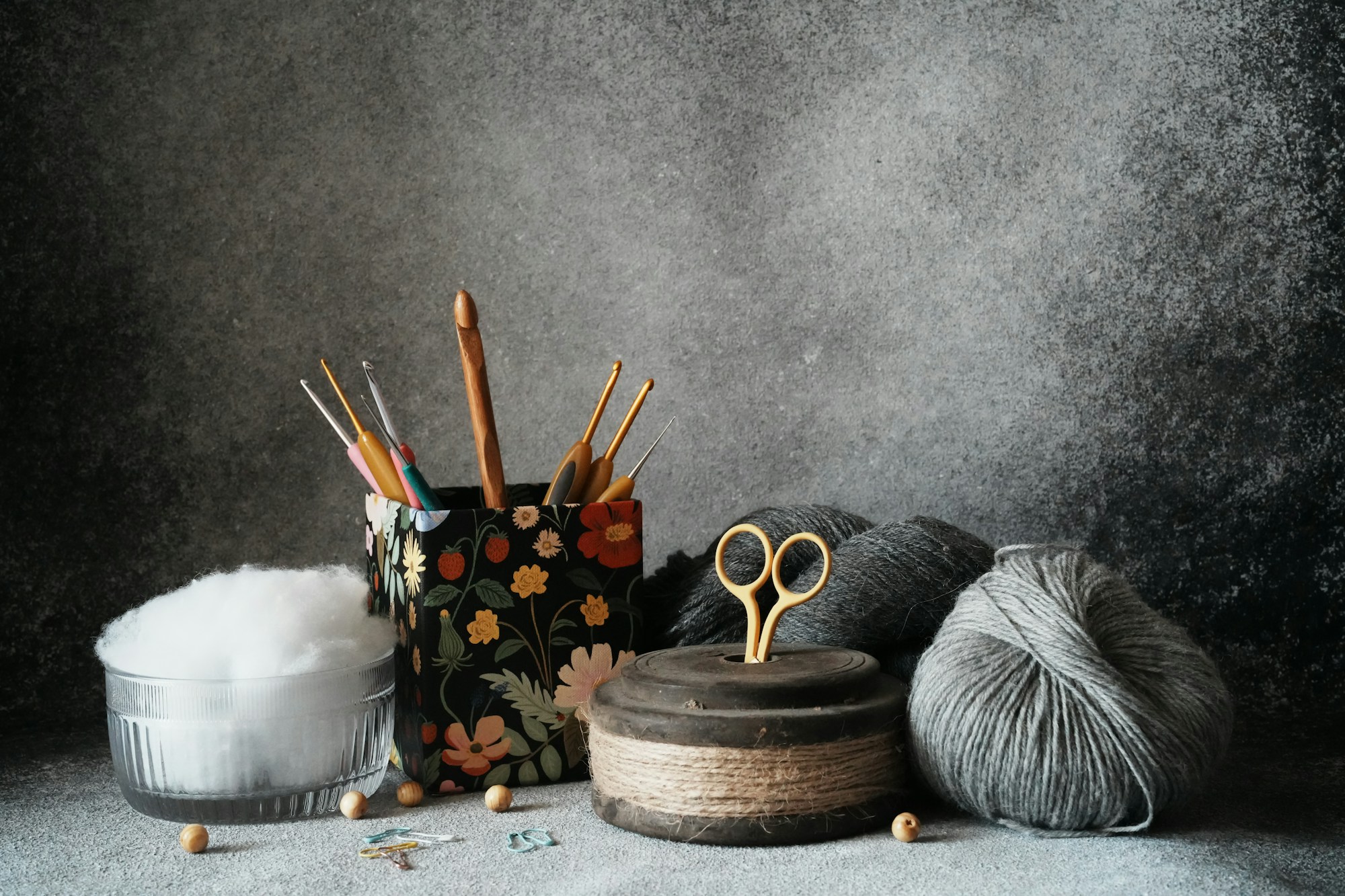 Dark moody flatlay of crochet yarn, hooks, and scissors